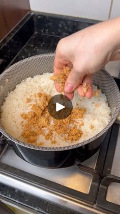 someone is adding seasoning to rice in a pan on top of the gas stove