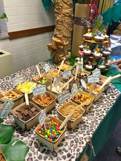 a table topped with lots of desserts and snacks on top of a leopard print table cloth