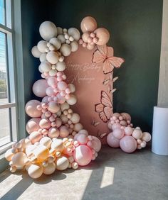 balloons are arranged in the shape of an arch with butterflies and flowers on it, next to a window