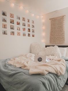 a bed with blankets, pillows and pictures on the wall above it in a bedroom