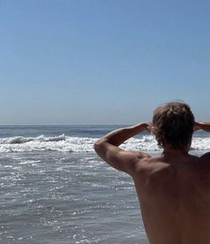 a man standing on top of a beach next to the ocean