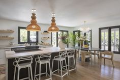 a kitchen with an island and bar stools next to windows that look out onto the backyard