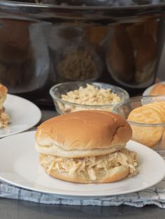 a chicken sandwich on a plate next to some macaroni and cheese in front of an instant pressure cooker