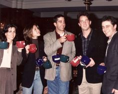 a group of people standing around each other holding cups