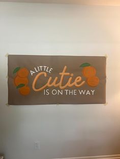 a sign that says,'little cutie is on the way'in oranges