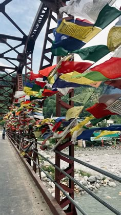 many colorful flags are hanging on the side of a bridge