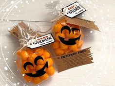 two bags filled with pumpkin candies sitting on top of a white wooden table next to each other