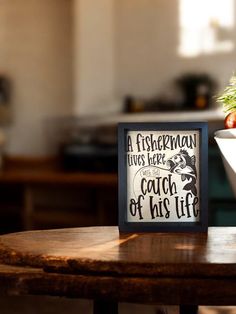 a table with a bowl of fruit and a sign that says fisherman lives here catch of his life