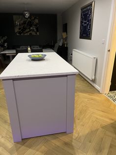 a kitchen island with a bowl of fruit on it in the middle of a room