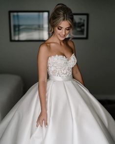 a woman in a white wedding dress is posing for the camera with her hand on her hip