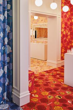 a brightly colored room with red, blue and yellow wallpaper on the walls next to two white pedestals