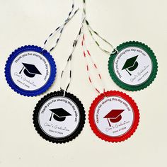 four graduation badges hanging from string on white surface