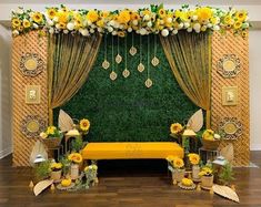 a decorated stage with yellow flowers and greenery on the wall, along with other decorations