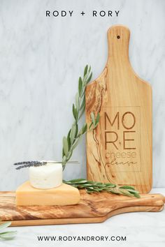 a cheese board and cutting board with olive leaves on it, next to a bottle of soap