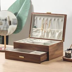 an open jewelry box sitting on top of a wooden table next to a mirror and other items