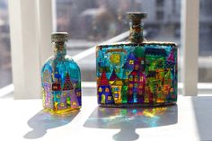 two colorful glass bottles sitting on top of a window sill next to each other