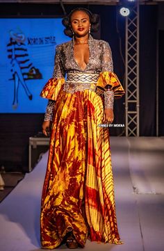 a woman is walking down the runway wearing a dress with an elaborate pattern on it