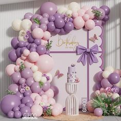 a birthday cake surrounded by balloons and flowers in front of a pink backdrop with butterflies