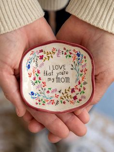 a person holding a small bowl with the words i love that you're my mom written on it