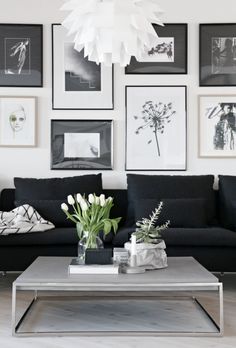 a living room with black couches and pictures on the wall