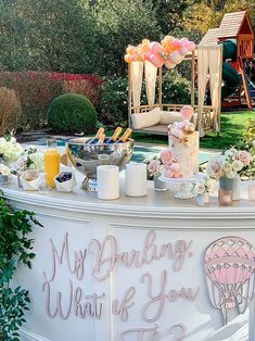 a table that has some food on top of it with balloons and flowers around it