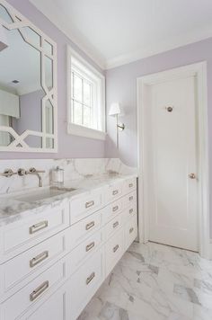 a bathroom with marble counter tops and white cabinets, along with a large mirror on the wall