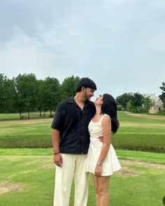 a man and woman standing next to each other in the grass