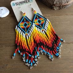 a pair of colorful beaded earrings sitting on top of a wooden table