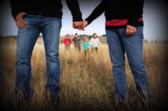 two people holding hands while standing in a field