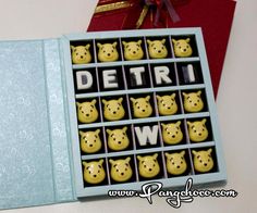 a box filled with yellow chocolates sitting on top of a white table next to a red envelope