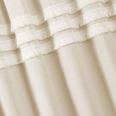 the curtain is white and has fringes on it's edges, as well as an eyelet