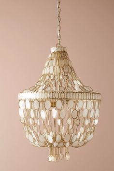 a white chandelier hanging from a gold chain with circles and dots on it