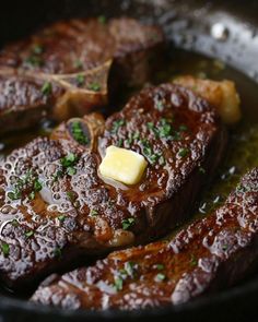 some steaks are cooking in a pan with butter and chives on top for garnish