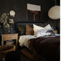 a bed room with a neatly made bed and two hanging lights above it's headboard