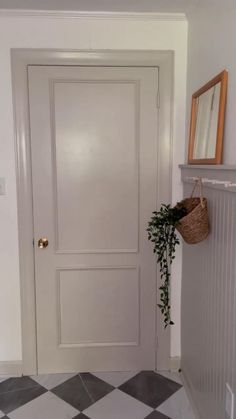 a white door with a basket hanging on it's side next to a black and white checkered floor