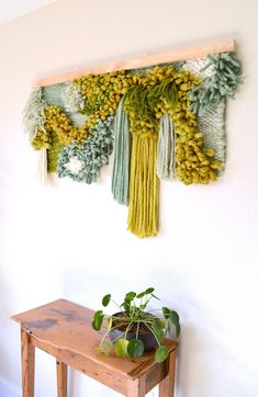 a wooden table topped with a potted plant next to a wall hanging