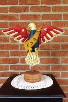 a statue of an eagle on top of a wooden table next to a brick wall