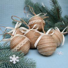 three brown balls with white lace on them sitting next to pine branches and snowflakes