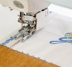 the sewing machine is working on an embroidered piece of fabric that has been stitched together