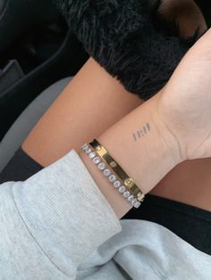 a woman's arm with a small diamond bracelet on her left wrist and the word i - n written across it