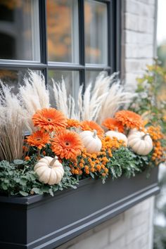 a window sill filled with lots of fake flowers and pumpkins on top of it