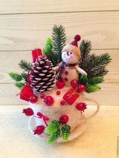 a snowman sitting on top of a cup filled with christmas decorations