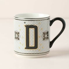 a black and white coffee cup with the letter d on it's front side