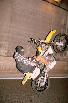 a man riding on the back of a dirt bike in mid air over a parking lot