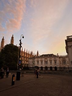 people are walking around in front of an old building with many spires on it