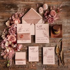 the wedding stationery is laid out on a wooden table with pink flowers and greenery