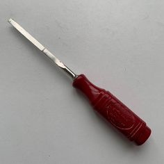 a small red object sitting on top of a white table next to a metal knife