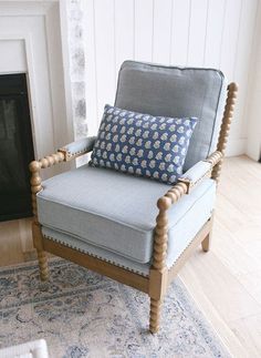 a chair sitting in front of a fire place with a pillow on top of it