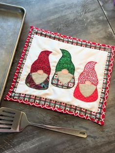 an oven mitt and spatula sitting next to a pot holder with gnomes on it