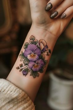 a woman's wrist tattoo with purple flowers on it